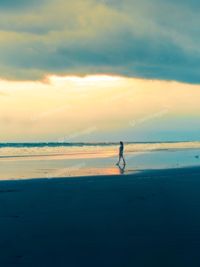 A Person Walking on the Beach during Sunset